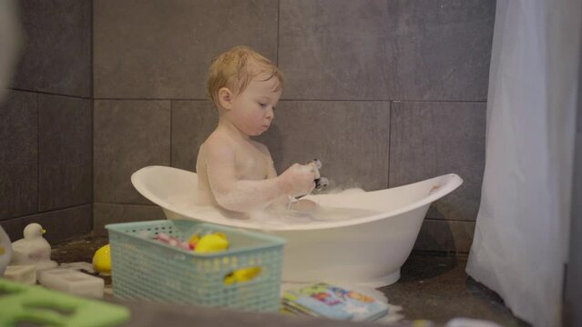 Lockdown Shot Of Boy Playing With Toy In Bathtub At Home - Fairbanks, Alaska