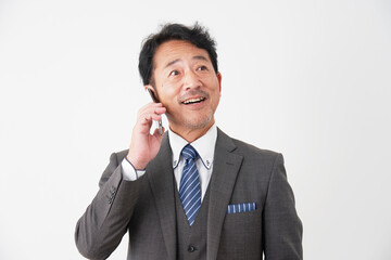 スマートフォンで電話する中年のビジネスマン　白背景