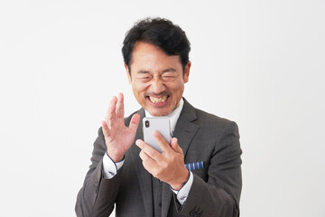 スマートフォンを見て笑顔で驚く中年のビジネスマン　白背景