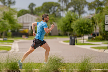 Male jogger running in park. Full length portrait of an athletic young man running outdoor. Sport and healthy lifestyle concept. Fitness man running in the city, male runner outdoors against the urban