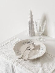 Christmas table setting - vintage plate, silver cutlery, glass and Christmas decor on a white table