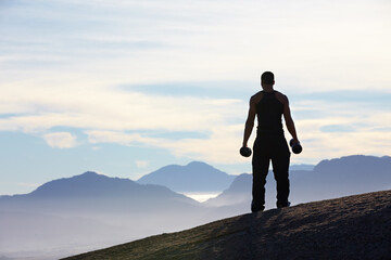 Fitness, weightlifting and back of man with dumbbells on mountain top for morning cardio on sky background. Weights, freedom and rear view of male bodybuilder in nature for training, power or workout