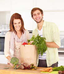 Couple, kitchen and vegetables for grocery shopping, unpacking and smile for food, nutrition and cooking. Man, woman and healthy in home, vegan, diet and package for vegetarian, produce and fresh