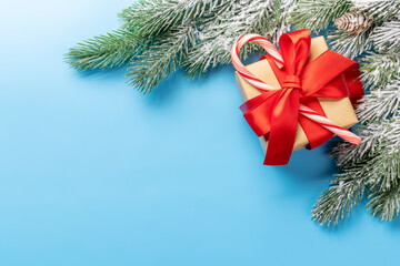 Fototapeta na wymiar Christmas fir tree branch and gift box over blue