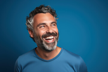 Fototapeta premium Handsome adult man with beard wearing casual hoodie sweater standing on isolated blue background smiling amazed laughing with surprised expression. Excited face human emotions concept
