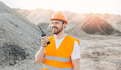 Happy Man Industry worker use walkie talkie on sand quarry, engineer of open pit mine