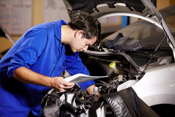 Fototapeta na wymiar Car, service and repair with a mechanic man in a workshop as an engineer looking at the engine of a vehicle. Garage, report or quote with a young technician working under the hood of an automobile