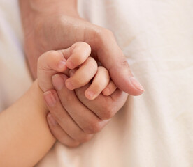 Parent, baby and holding hand for comfort on bed for love, trust or support in bond. Person, infant and caring with touch for child development, growth or health in wellness for quality time together