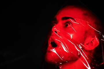 Man, red plastic and suffocate in studio isolated on a black background mockup. Polyethylene, film...