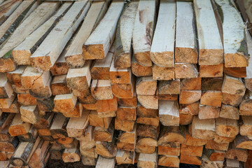 Piles of wood from logging forests to be used as raw materials for furniture. Piles of round and square wood form patterns and textures.