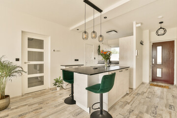 a kitchen with wood flooring and white walls in the center of the room there is a green bar stool next to the counter