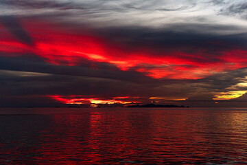 The sun's rays painted the clouds and the sea with scarlet colors