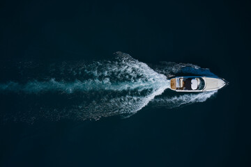 Drone view of a yacht sailing. Top view of a white boat sailing to the blue sea. Motor yacht in the sea. Travel - image.