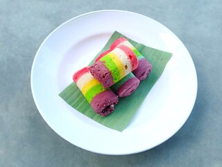 roll cake. Sweet cake. Mini rainbow roll cake on plate over gray background. 