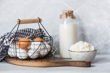 Fresh dairy products, milk, cottage cheese, eggs in stylish ceramic dishes on a gray background. The concept of natural, dietary nutrition. Useful products.