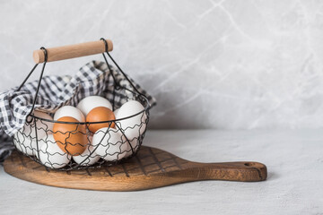 Fresh farm eggs in a stylish vintage iron basket on a gray background. The concept of natural, healthy nutrition. Useful products.