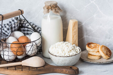 Fresh dairy products, milk, cottage cheese, cheesecakes, eggs in stylish ceramic dishes on a gray background. The concept of natural, dietary nutrition. Useful products.