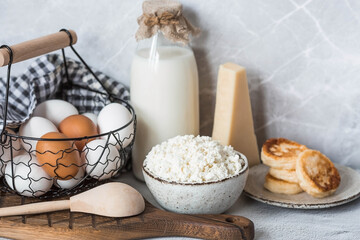 Fresh dairy products, milk, cottage cheese, cheesecakes, eggs in stylish ceramic dishes on a gray background. The concept of natural, dietary nutrition. Useful products.