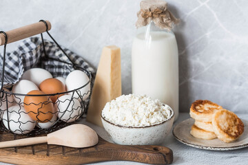 Fresh dairy products, milk, cottage cheese, cheesecakes, eggs in stylish ceramic dishes on a gray background. The concept of natural, dietary nutrition. Useful products.