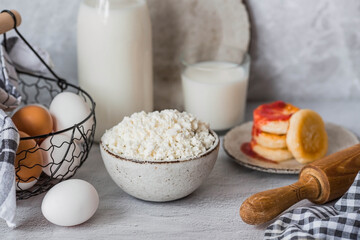 Fresh dairy products, milk, cottage cheese, cheesecakes, eggs in stylish ceramic dishes on a gray background. The concept of natural, dietary nutrition. Useful products.