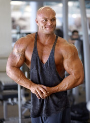 Body builder, flex and man in a gym with power, weightlifting and strength at a sport club. Muscle,...