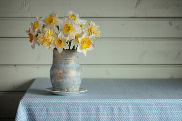 a bouquet of garden daffodils in a vase on the table in the cottage