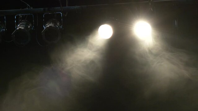 bright spotlight shining through stage smoke. Lights and smoke. Row of white lights from a stage. Theatrical scene without actors, scenic colorful light and smoke