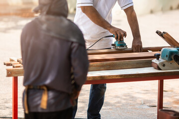 Selective focus to carpenter's hands smoothing a wooden surface with an electric planer.