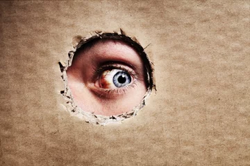 Foto op Aluminium Closeup, cardboard and eye spy on hole, peek and search on mockup space. Face, macro and man peeping through paper board for secret, security and watch for surveillance, discover mystery and privacy © Nicola Katie/peopleimages.com