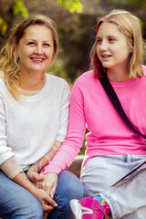 mom and daughter teenager cheerful portrait in the park on a walk close-up on an autumn day