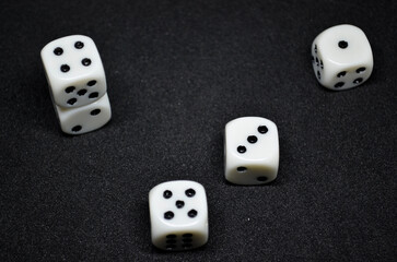 White dice are small, cube-shaped gaming accessories, on black background, They have blackpips on...