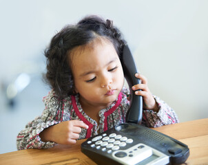 Playing, serious and a child on a telephone phone call for communication in a house. Home, contact...