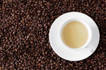 Top view of espresso with coffee foam in a cup on a dark background from coffee beans
