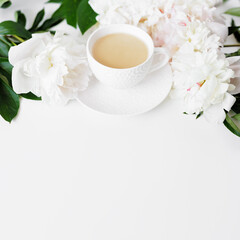 Obraz na płótnie Canvas Morning coffee cup and white peonies flowers on white table