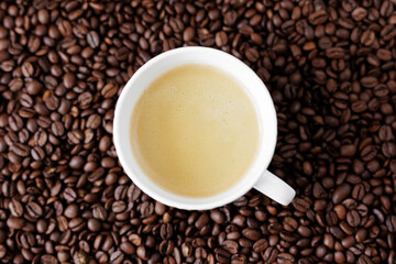 Top view of coffee in a cup on a dark background from coffee beans