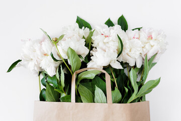 Beautiful white peonies in brown paper bag