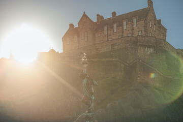 Edinburgh a majestic castle silhouetted against a stunning sunset with a statue in the foreground