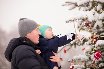 Portrait of father with a cute boy next to a Christmas tree decorated at Christmas. Christmas and...