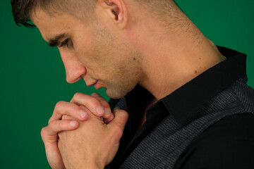 Fototapeta premium emotions of a handsome man guy on a green background chromakey close-up dark hair young man. Permacrisis, life problems, financial parties concept. Pensive young man leaning on his hands