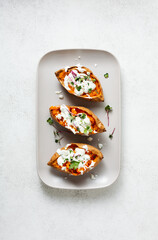 Oven-baked sweet potatoes with spices, herbs and sour cream. Top view. Copy space.