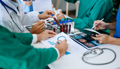 Medical team having a meeting with doctors in white lab coats and surgical scrubs seated at a table...