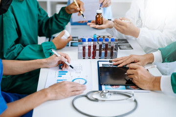 Medical team having a meeting with doctors in white lab coats and surgical scrubs seated at a table discussing a patients working online using computers in the medical industry