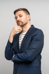 Serious stylish charismatic man looking like successful manager, businessman, entrepreneur, freelancer, employee, executive, marketer. Pensive unshaved man touching chin looking confidently at camera