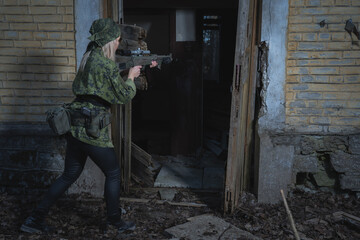 A military sniper girl assault a building in the twilight.
