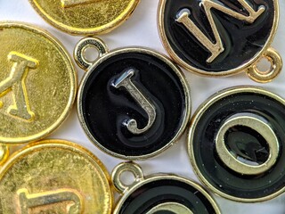 Black and gold initial 'J' pendant in the middle of several letters