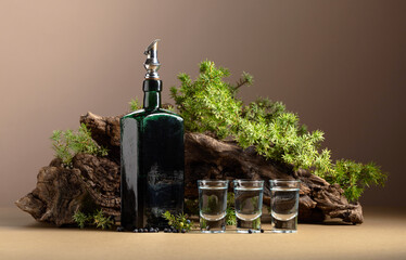 Gin in vintage bottle on a background of old snags and juniper branches.