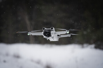 Mini drone with a camera in the air during snowfall in winter.