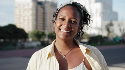 Pretty young African American latin woman portrait looking at camera smile in the urban city street