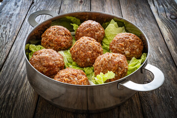Lion's head meatballs - uncooked big meatballs with vegetables in stem pot on wooden background 