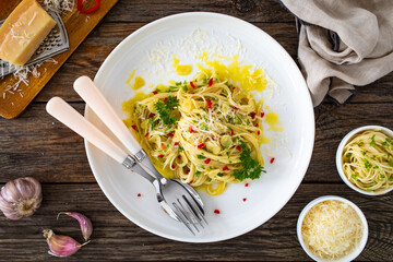 Spaghetti aglio e olio with parmesan and garlic on wooden table
